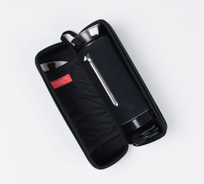 Top-down view of The Pakt Coffee Kit in an open black zippered case with stainless-steel frother, spare lid and metal straw