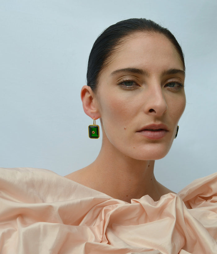 Model on blue backdrop wears voluminous peach-colored top with Tile Earrings in Forest.