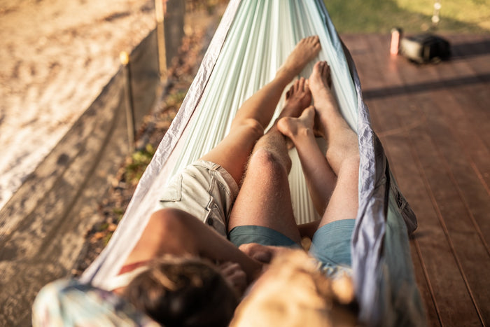 Twilight Blue recycled hammock with white straps, person relaxing in striped fabric outdoors.