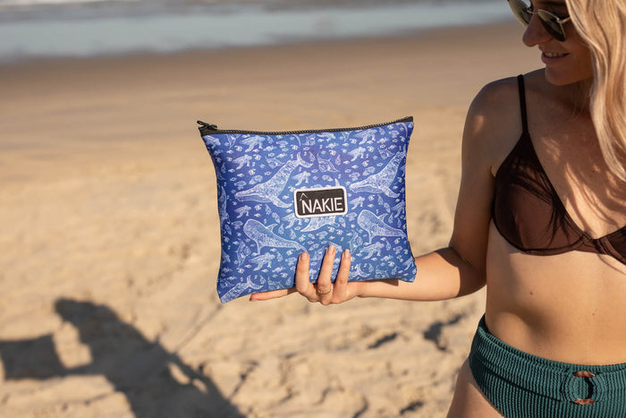 Blue recycled sand-free beach towel with underwater sea creature print, held by woman at beach