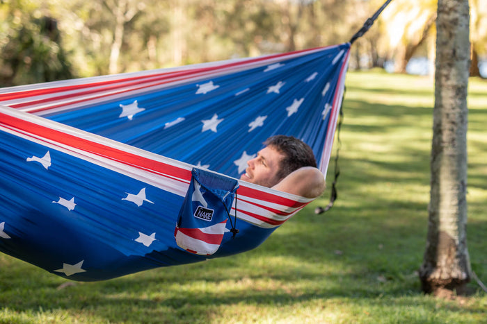 American flag recycled hammock with straps, person relaxed inside outdoor park setting