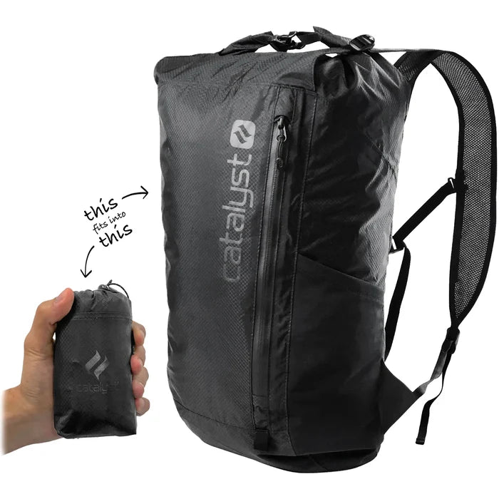 A hand holds a small black pouch with the Catalyst Case US logo, showing the Waterproof 20L Backpack in Stealth Black fits inside. The backpack features a front zipper, side pocket, padded strap, and an arrows-and-text highlight its compact foldable design.