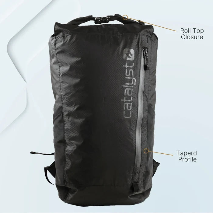 The Catalyst Case US Waterproof 20L Backpack is black with a roll-top closure, a diagonal front zipper, and "catalyst" printed vertically. Labels highlight the “Roll Top Closure” at the top and “Tapered Profile” at the bottom on a minimal light background.