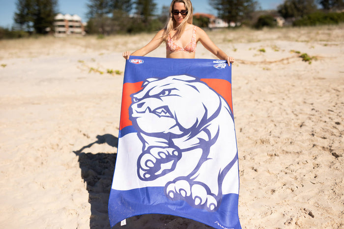 Western Bulldogs AFL beach towel in blue and orange with white bulldog logo, sand-free microfiber material, displayed on beac