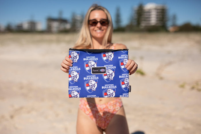 Western Bulldogs blue beach towel with repeated logo and bulldog emblem pattern, held up on sandy beach