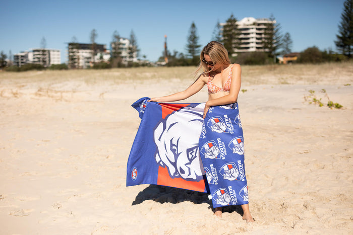 Western Bulldogs AFL recycled sand-free beach towel in blue with white bulldog logo, displayed on sandy beach