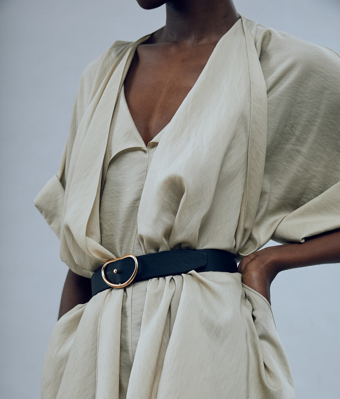 Model on grey backdrop wears draped tan shirt with Wide Georgia Belt in Black.