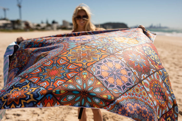 Colorful patterned XL beach blanket with geometric and mandala designs in orange, blue, and gold tones